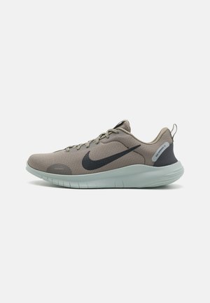 Chaussure de course Nike gris clair avec logo swoosh noir, tige en maille, fermeture à lacets et semelle blanche rembourrée vue de profil.