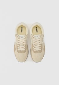 Beige and cream sneakers with suede and mesh materials, round toe, classic lace-up design, and rubber sole. "HUGO" logo on the insole.