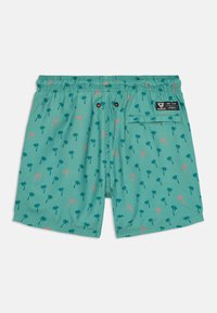 Pantaloni da bagno turchesi con un motivo di palme in verde e rosa. Presentano un elastico in vita con cordoncino e una tasca sul retro.