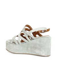 Sandalo con zeppa verde in suede, design a fasce incrociate e fibbia regolabile. Presenta una suola piattaforma e una superficie testurizzata.
