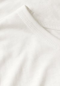 T-shirt en coton blanc avec une texture douce, présentant un col en V et des bords à coutures plates pour une finition propre.