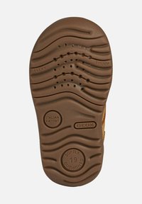 Sole di una scarpa marrone per bambini con battistrada ondulato, fori di ventilazione e iscrizioni "FLEXY SYSTEM," "PATENTE ITALIANA," "GEOX," e "IMBOTTITURA SOFFICE 19."