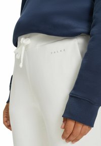 Die weißen Sweatpants von FALKE verfügen über einen gerippten Bund mit einem Kordelzug und werden mit einem navyfarbenen Sweatshirt kombiniert, das eine strukturierte Oberfläche und gerippte Bündchen aufweist.