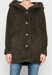 Oliven grøn faux fur frakke med hætte, knaplukning og sidelommer. Har en blød tekstur og vide ærmer.