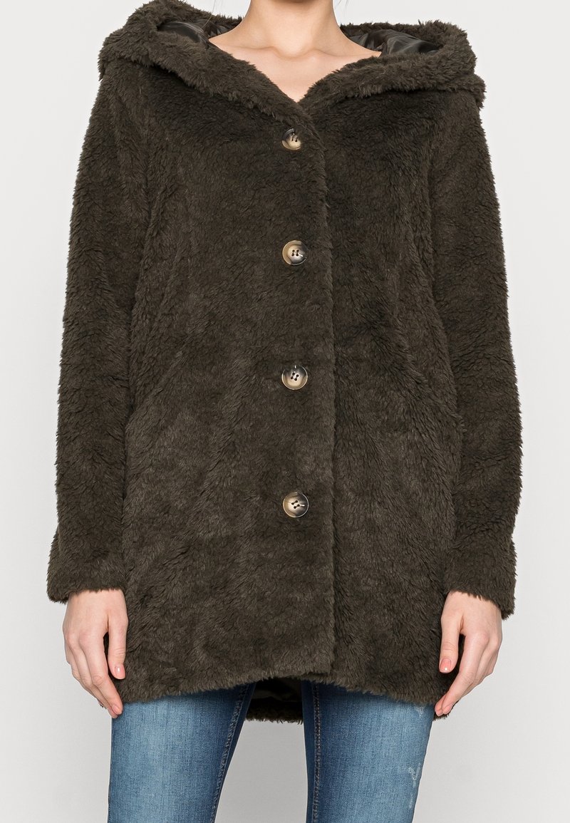 Oliven grøn faux fur frakke med hætte, knaplukning og sidelommer. Har en blød tekstur og vide ærmer.