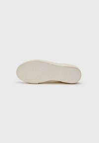 Semelle de chaussure en off-white avec une surface texturée et à motifs. Avant légèrement arrondi et bord de talon contourné, conception plate sans marquage visible.