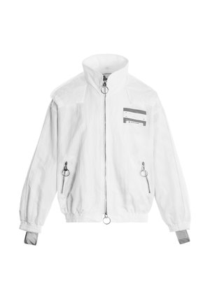 Chaqueta blanca con cremallera y cuello alto, dos bolsillos delanteros con cremallera y tiradores redondos, puños elásticos y una pequeña parche rectangular en el pecho.