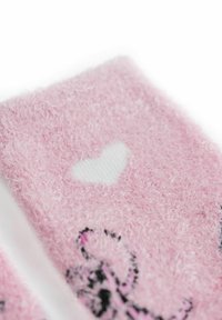 Calze rosa pelose con superficie testurizzata e un'apertura a forma di cuore. Presentano accenti di motivo nero e rosa. Materiale morbido e accogliente.