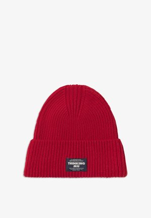 Rode geribbelde gebreide beanie met omgevouwen rand en zwart label met de tekst "Thinking Mu" op een witte achtergrond.