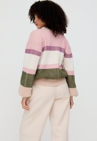 Gestrickter Pullover mit vertikalen Streifen in Rosa, Weiß, Lila und Olivgrün. Gerippte Textur und übergroße Ärmel. Einheitlicher rosa Saum am unteren Rand.