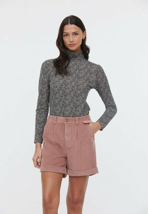 Haut à col roulé floral gris et short en velours côtelé rose avec ourlets retroussés, comprenant des poches latérales, des détails de couture et une fermeture par boutons sur le devant.