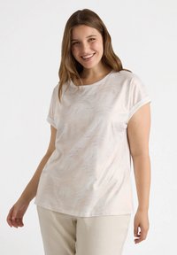 Top de manga corta en tejido color crema claro con patrones de textura en forma de olas. Cuello redondo y puños enrollados, combinado con pantalones color beige claro.