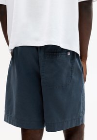 Marineblaue Baumwollshorts verfügen über eine Gesäßtasche mit einem kleinen Logotag, einen lässigen Schnitt und einen geraden Saum. Der Bund ist elastisch für mehr Komfort.
