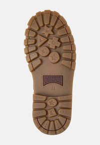 Brown rubber shoe sole features various geometric patterns and textures; includes "Camper" branding and star, triangle, and circle shapes.