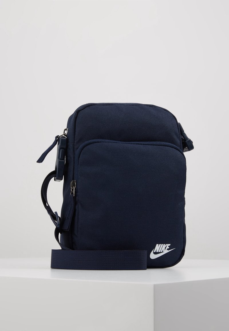 Námořnická nylonová crossbody taška s hlavní kapsou na zip, přední kapsou, nastavitelným popruhem a bílým logem Nike v pravém dolním rohu.