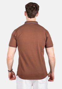 Bruine poloshirt met een effen kleur, contraststiksels bij de kraag en mouwen, korte mouwen en een relaxte pasvorm.
