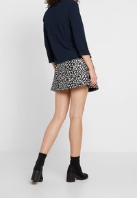 Navy three-quarter sleeve top paired with a black and white floral skater skirt. Model wears black ankle boots with chunky heels.