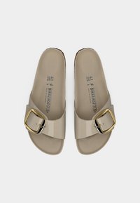 Ζευγάρι μπεζ σαγιονάρες Birkenstock με μεγάλη χρυσή αγκράφα, εσωτερικό πέλμα με ανάγλυφη μορφή και σημάδια μεγέθους 41 στο εσωτερικό.