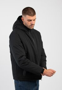 Schwarze Kapuzenjacke mit einem Reißverschluss auf der Vorderseite, die ein einfaches Design, lange Ärmel und Taschen an den Seiten aufweist. Glatte Textur mit einem warmen Aussehen.