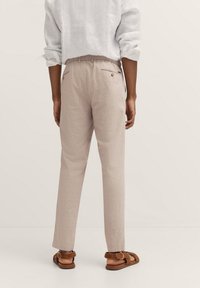 Helle beige Leinenhosen mit lockerer Passform, ausgestattet mit einem Kordelzugbund, zwei Gesäßtaschen und einer glatten Textur.