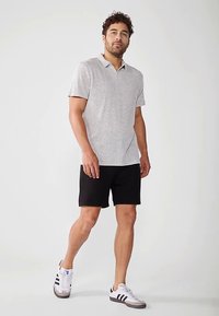 Hall halli lühikeste varrukatega polosärk kraega, mustade lühikeste pükstega. Komplekti kuuluvad valged tossud mustade ja hallide detailidega.