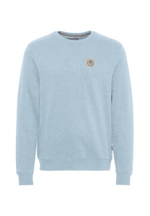 Sudadera azul claro de manga larga con cuello redondo, puños acanalados y un pequeño parche beige con el logo en el pecho izquierdo.
