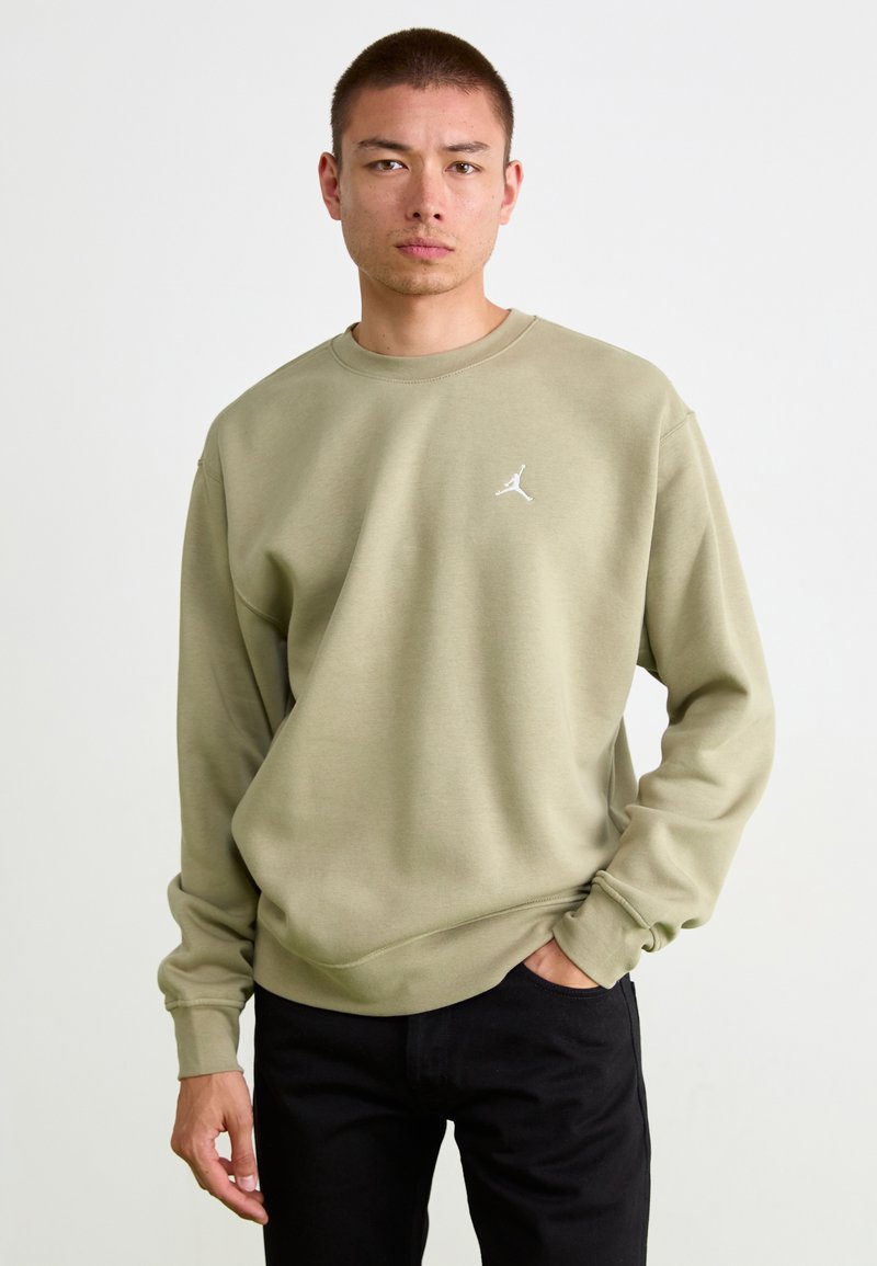 Olivengrøn sweatshirt med rund hals og ribstrik ved ærmerne, der har et lille hvidt Jordan-logo på brystet. Bæres med sorte bukser.
