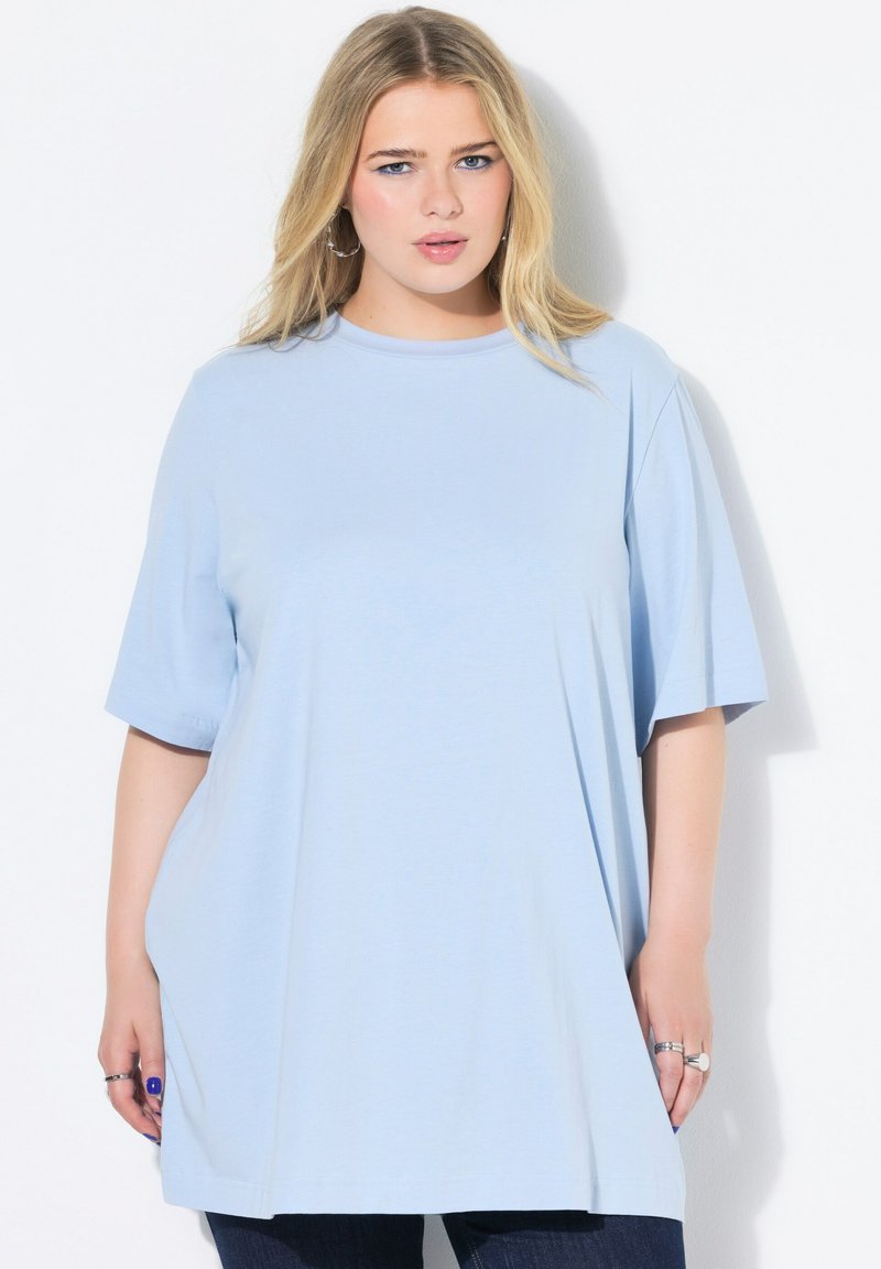 Světle modré oversized tričko z měkké tkaniny, s krátkými rukávy a kulatým výstřihem. Hladká textura s uvolněným střihem.