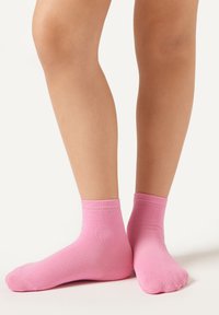 Lyserøde ankelstrømper lavet af blødt bomuldsblandingsmateriale, med en ribbet kant, glat tekstur og standard pasform for komfort og åndbarhed.