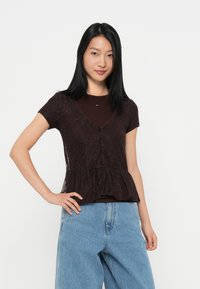 Kanten peplumtop in donkerbruin, met korte mouwen, een knoopsluiting aan de voorkant en gelaagde textuur over een effen shirt.