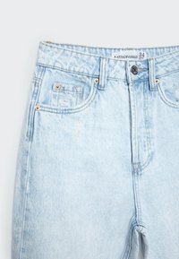 Jeans de denim azul claro con cintura alta, cuatro bolsillos y un sutil acabado desgastado en el frente. Incluye detalles de metal.