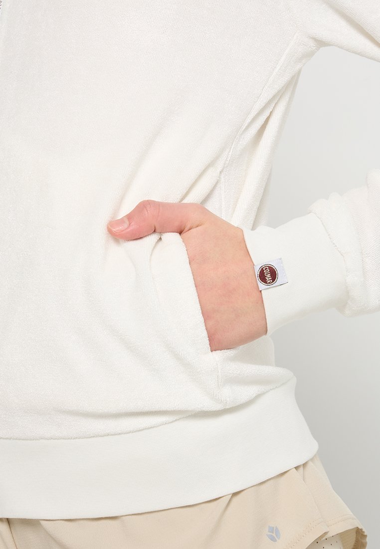 Felpa bianca in pile con tasca a marsupio, polsini e orlo a costine, e un piccolo etichetta logo sulla manica. Tessuto morbido con una vestibilità rilassata.