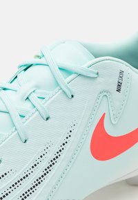 Lyseblå fodboldstøvler med et tekstureret Nikeskin-materiale, kontrasterende orange Nike swoosh og mønstrede detaljer langs overdelen.
