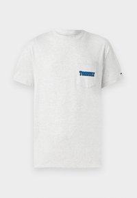 Svetlo šedé tričko s krátkymi rukávmi a náprsné vrecko, ktoré má modré logo "TOMMY Jeans" a malú Tommy vlajku na ľavom rukáve.