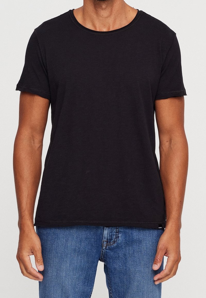 Svart kortärmad T-shirt med rund hals, tillverkad av mjukt bomullstyg. Har rullade ärmslut och en avslappnad passform.