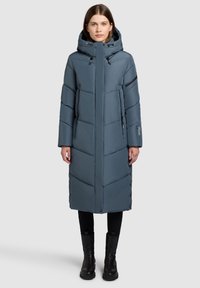 Gevoerde lange jas in blauw-grijs, met een ritsluiting, grote capuchon, rits- en knoopaccenten en verticale stikpatronen.