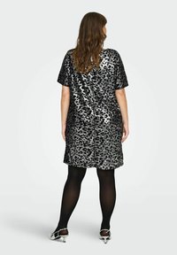 Trumpa rankovėmis suknelė juodos ir sidabro blizgučiais su leopardų raštu. Yra laisvo kirpimo ir iki kelių ilgio, derinama su juodomis pėdkelnėmis.