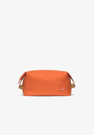 Trousse de toilette rectangulaire orange avec boucles latérales, fermeture éclair sur le dessus et petit patch de marque dans le coin avant droit.