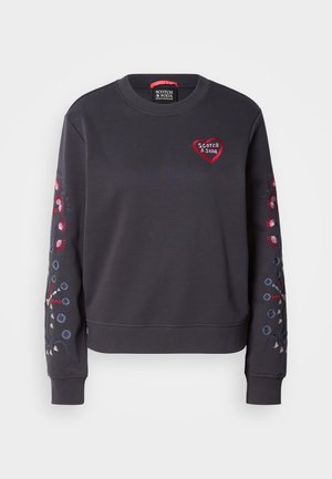 Mørkegrå hettegenser med rund hals, med rødt hjerte-logo og fargerik blomsterbroderi på ermene. Myk stoff, ribbestrikkede mansjetter.