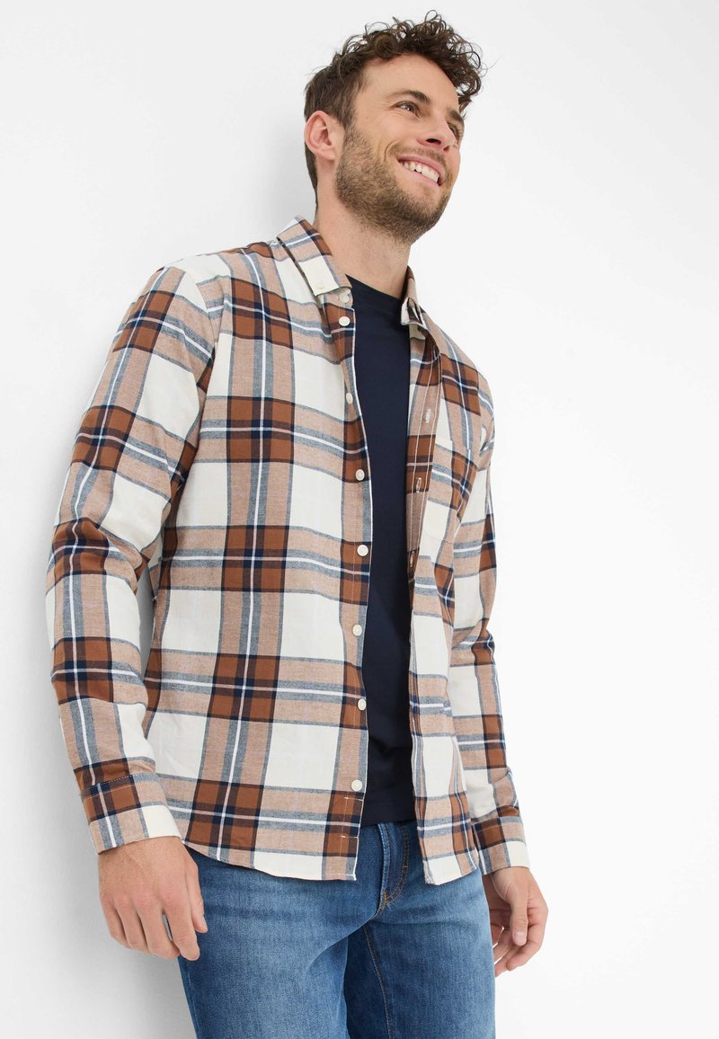 Kariertes Hemd in Beige-, Braun- und Blautönen; lange Ärmel, knöpfbare Front, lässige Passform; kombiniert mit einem navyblauen T-Shirt und blauen Jeans.