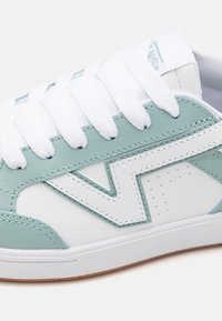 Světle zelené a bílé tenisky vyrobené z kůže a gumy. Mají ploché bílé tkaničky, perforovaný design a výrazný detail s logem značky.