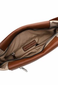 Intérieur d'un sac en cuir marron avec une doublure beige lisse, comportant une fermeture éclair et une étiquette en cuir de marque. Points de données incluent la texture et la couleur.
