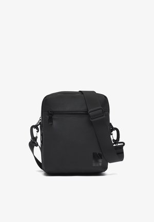 Schwarze rechteckige Umhängetasche mit verstellbarem Riemen, vorderer Reißverschlusstasche und dezentem Logo in der unteren rechten Ecke.