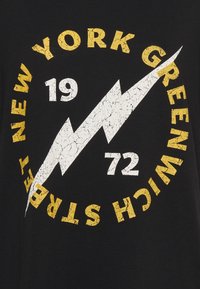 Černé tričko s opotřebovanou grafikou a žlutým a bílým textem "NEW YORK GREENWICH STREET" a designem blesku.