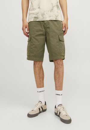 Olivgrüne Cargo-Shorts aus Baumwolle mit mehreren Taschen. Getragen mit einem beige gefärbten T-Shirt und weißen Socken, die Logo-Text zeigen.