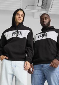Sudaderas negras con capucha y rayas horizontales blancas, que presentan un gran logo impreso de "PUMA". Incluyen bolsillos delanteros tipo canguro y cordones.