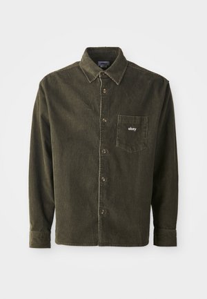 Camisa de pana verde oscuro con un frente abotonado, cuello puntiagudo y un bolsillo en el pecho que presenta un bordado blanco de "obey".