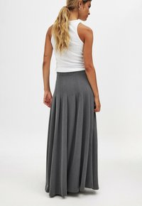 Grauer Maxirock mit Falten, aus weichem Stoff. Der Bund ist angepasst und sorgt für ein fließendes Design, das bis zu den Knöcheln reicht.