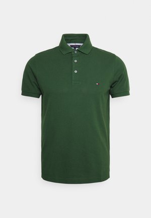 Polo vert à manches courtes avec trois boutons et un petit logo rouge, blanc et bleu sur le côté gauche de la poitrine.