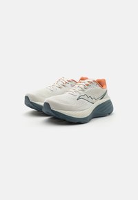 Des chaussures de course avec une tige en mesh légère et respirante en blanc, une semelle en caoutchouc grise et des accents corail sur le col. Présente un design courbé.